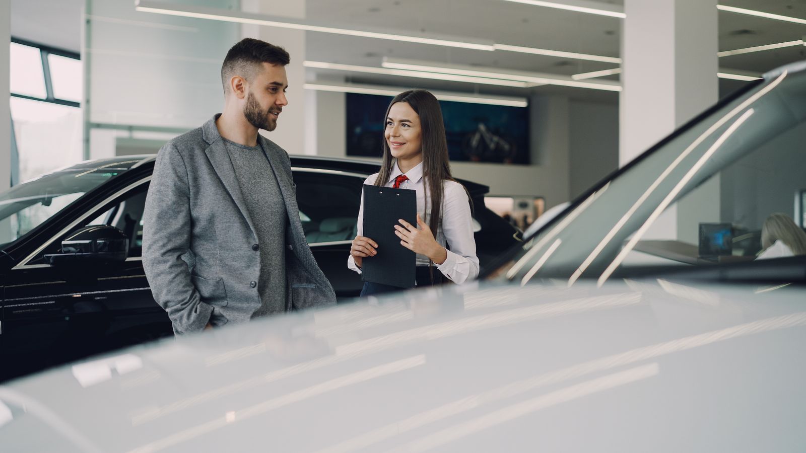 Client échangeant avec une conseillère dans un showroom automobile
