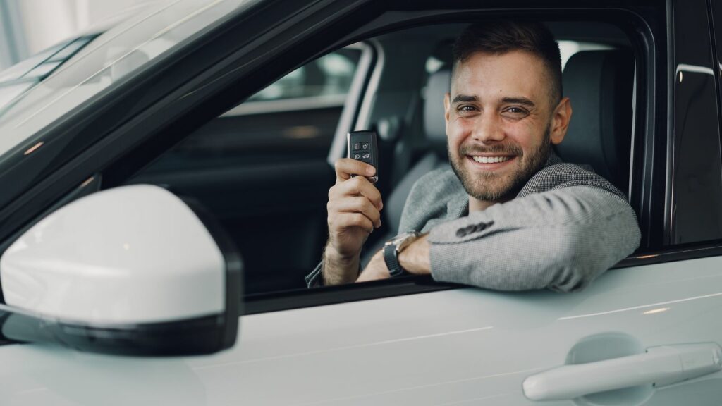 Client souriant dans une voiture tenant ses clés