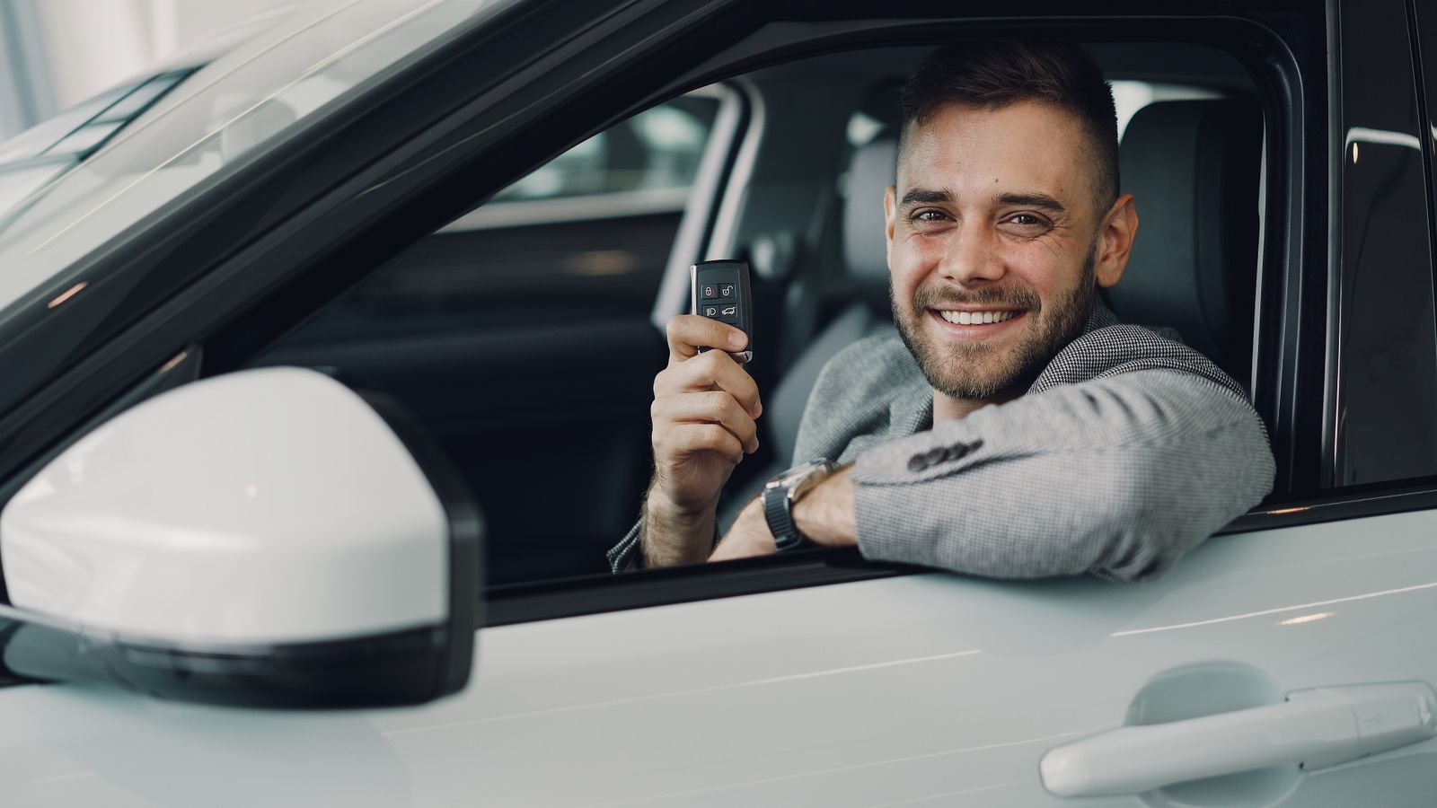 Client souriant dans une voiture tenant ses clés